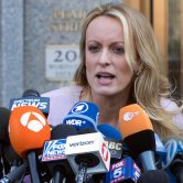 Stormy Daniels speaks into more than a dozen microphones with news outlet logos in front of a courthouse in New York.