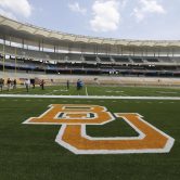 More than a dozen people stand on the football field at Baylor University's McLane Stadium.