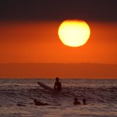 Surfers wait for waves as the sun goes down in Newport Beach, Calif.