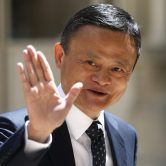 Jack Ma raises his hand while walking.
