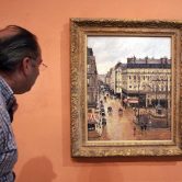 A visiter views Camille Pissarro's painting "Rue St.-Honore, Apres-Midi, Effet de Pluie."