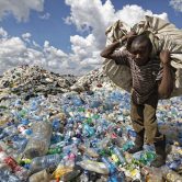 A man walks on a mountain of plastic bottles in Kenya.