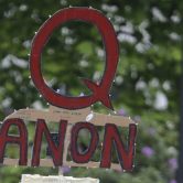 A person carries a QAnon sign at a protest rally in Olympia, Wash.