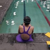 A transgender girl swimmer sits next to a pool in Utah.