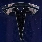 A Tesla emblem is displayed on one of the company's vehicles.