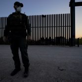 Border Patrol agent stands in front of wall