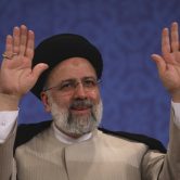 Ebrahim Raisi waves to participants at the conclusion of a press conference.