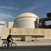 A worker rides a bicycle in front of the Bushehr nuclear power plant.
