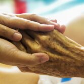 This photo shows someone holding the hand of a dying person.