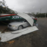 Vehicles lay under a metallic structure brought down by the winds of Hurricane Grace in Mexico.