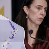 Prime Minister Jacinda Ardern holds a Covid-19 map during a press conference.