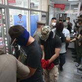 Four wanted Thai policemen arrive for interrogation.
