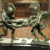 A bronze sculpture of two demigods carry a deceased man.