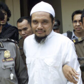 Militant cleric Abu Rusdan is escorted by security officers after his trial hearing in 2003.