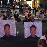 Two people hold posters showing images depicting Elijah McClain.