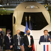 French President Emmanuel Macron speaks in front of a life-size replica of the next high-speed train TGV.