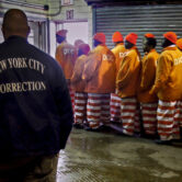 Detained men from the Rikers Island jail are supervised by a corrections officer