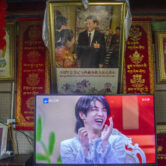 A television shows a Chinese talk show program underneath a photo of Chinese President Xi Jinping