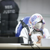 The 96-year-old defendant Irmgard F. sits behind a plexiglass screen in a courtroom.