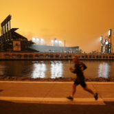 A jogger runs near Oracle Park in San Francisco under darkened skies from wildfire smoke.