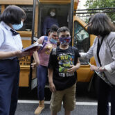 Masked children disembark from school bus.
