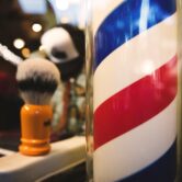 A hair brush sits next to a barber's pole.