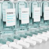 A row of Covid-19 vaccine vials and syringes.