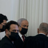 Benjamin Netanyahu is flanked by lawyers before testimony by a witness in his trial.