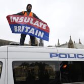 A climate protester stands on a police van in London