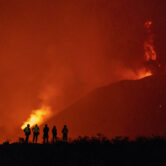 People look as lava flows from a volcano as it continues to erupt on La Palma, Spain.