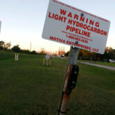 Signs mark a light hydrocarbon pipeline near a neighborhood in Port Arthur, Texas.