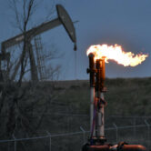 A flare to burn methane from oil production is seen on a well pad.