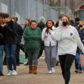 Parents walk away with their kids following an active shooter situation at Oxford High School.