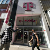 A man uses a mobile phone outside a T-Mobile store.