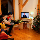A family watches Emmanuel Macron give an interview on television in France.