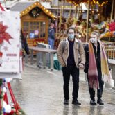 People wearing face masks walk through a Christmas market in England