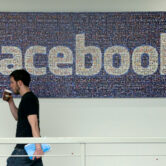 A Facebook employee walks past a sign at the company’s headquarters.