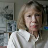 Joan Didion sits in front of a photo of herself holding her daughter, Quintana Roo.