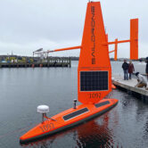 A Saildrone Explorer ocean drone is prepared for launch at a dock in Newport, R.I.