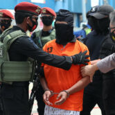 Police escort suspected militant Zulkarnaen at an airport in Indonesia.