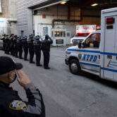 NYPD officers salute during the transfer of the remains of officer Wilbert Mora.