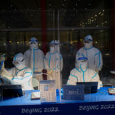 Olympic workers in protective gear at the Beijing Capital International Airport.