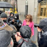 Sarah Palin stands outside a concrete building in the rain.