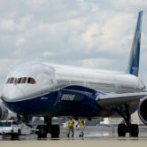 Boeing employees walk a Boeing 787-10 Dreamliner toward a delivery ramp.