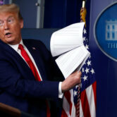 Donald Trump holds up papers during a press briefing.