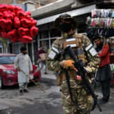 A Taliban fighter passes in front of red heart-shaped balloons for Valentine's Day.