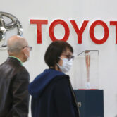 People walk past the logo of Toyota at a showroom in Tokyo.