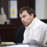 Travis Reinking sits in court during his murder trial.