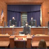 Six justices of the Massachusetts high court stand wearing masks in preparation for oral argument