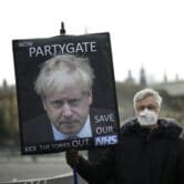 An anti-Conservative Party protester holds a placard with an image of Boris Johnson.